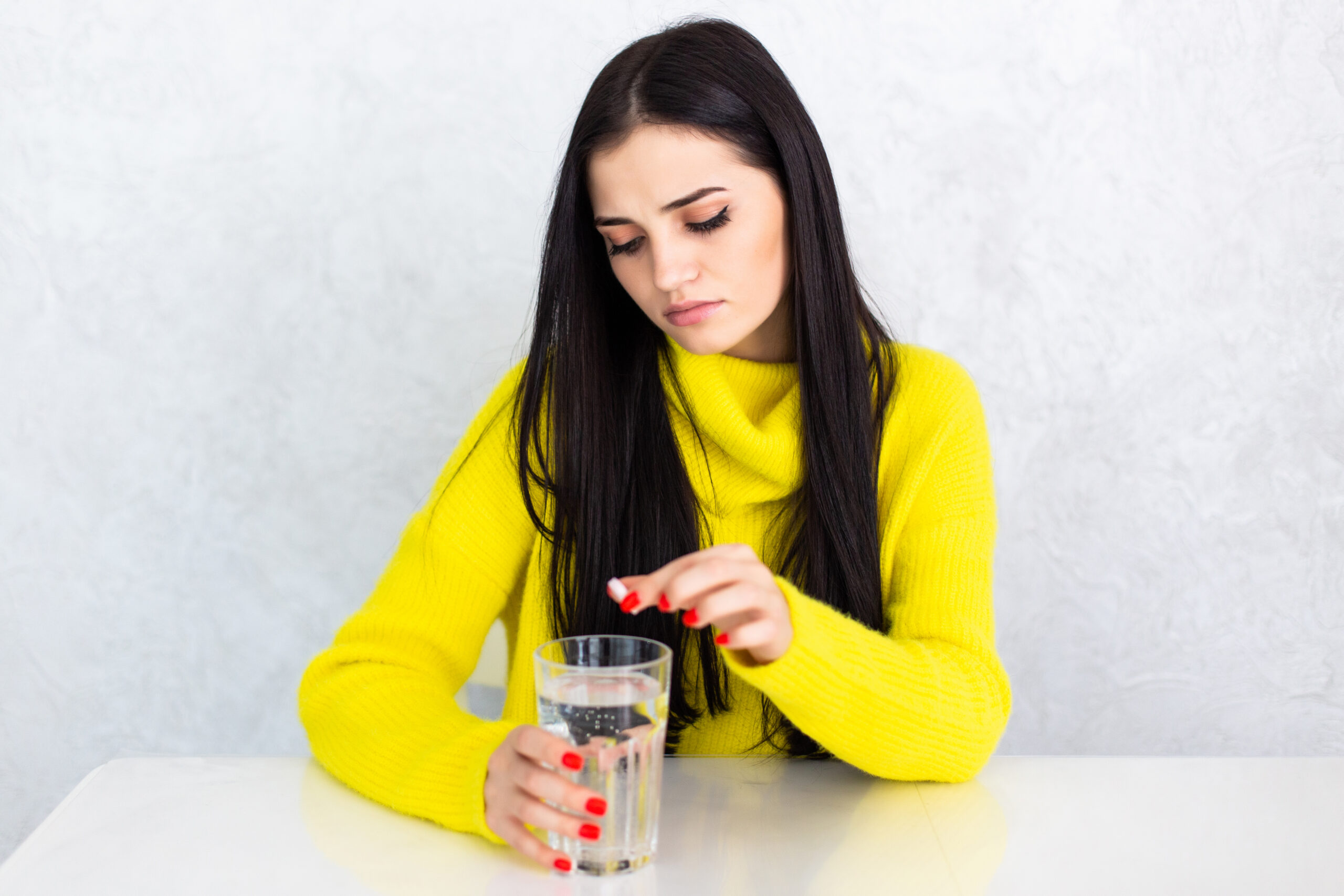 Woman taking a hypertension supplement with water